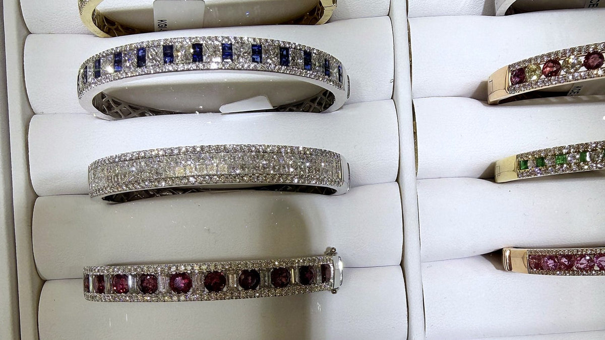 A tray of gem-set bangles at Benji Designs — sapphire, ruby, emerald and diamond, in white, yellow and rose gold.